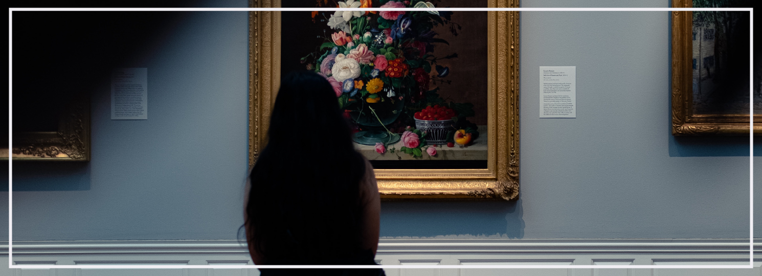 woman sitting in an art gallery admiring a studio floral painting